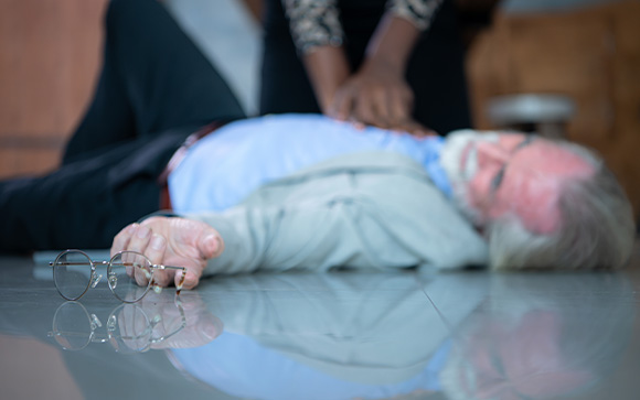 hands performing CPR on an unconscious person with a medical device attached demonstrating emergency response 3 steps
